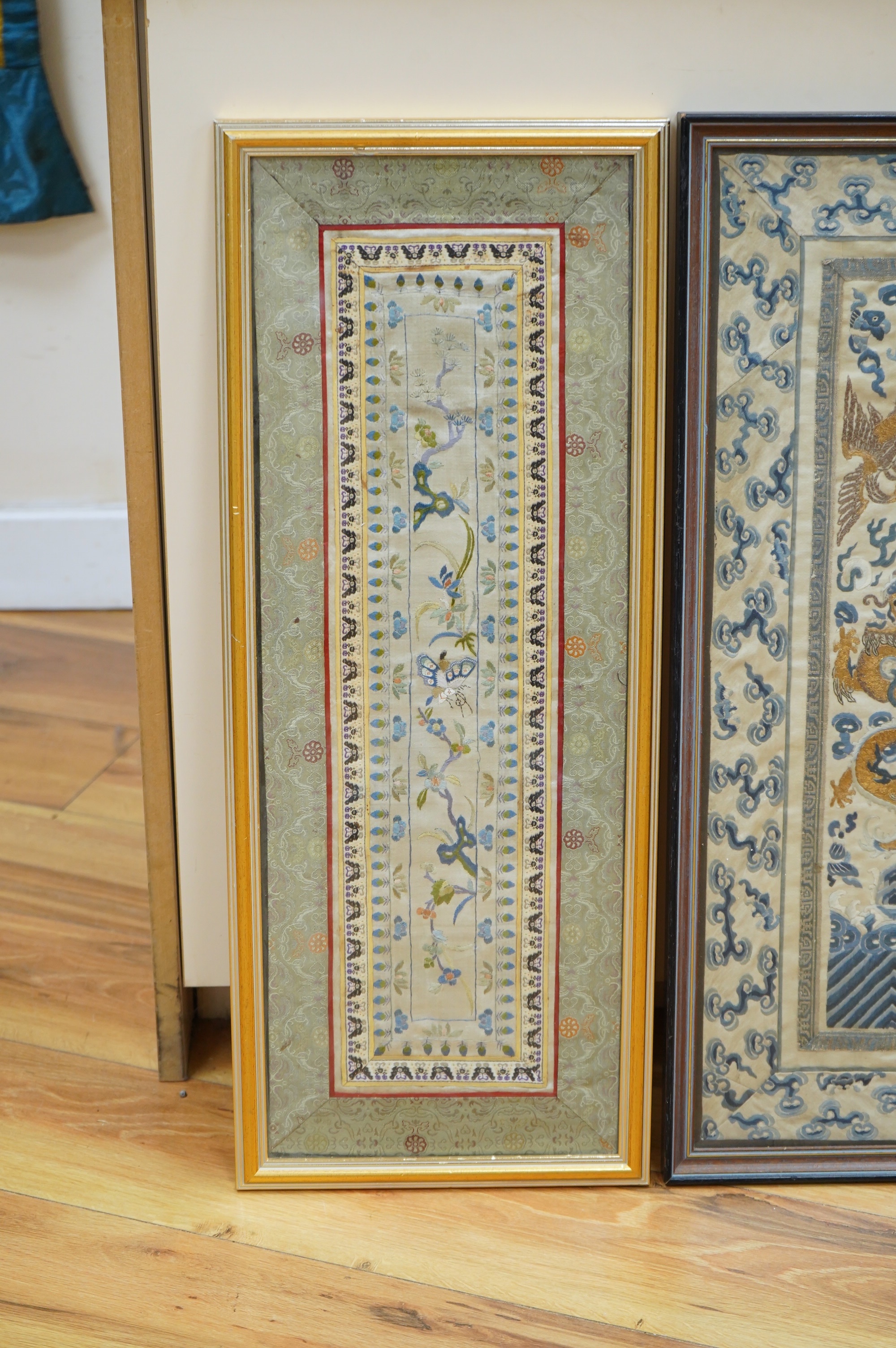 Two framed pairs of early 20th century Chinese silk embroidered sleeve bands; one pair embroidered in blue with Chinese knot as ornate bat motifs surrounded by floral motifs, edged in fine braiding and a black satin, sil